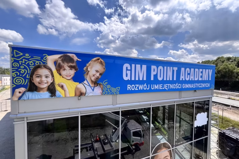 Baner reklamowy na elewacji obiektu sportowego — druk wielkoformatowy Ad Colors